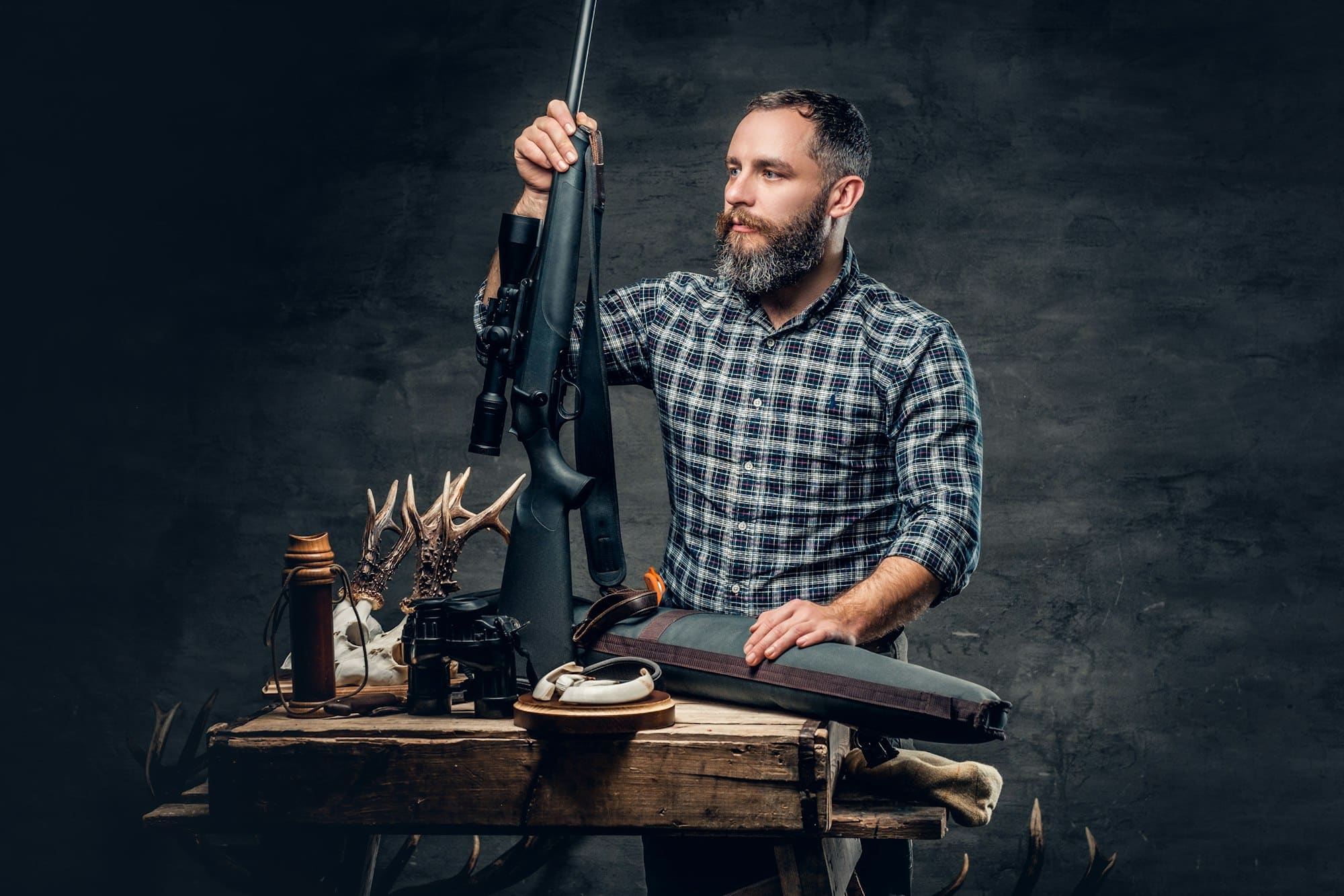 Bearded modernl hunter with his trophy holds a rifle.