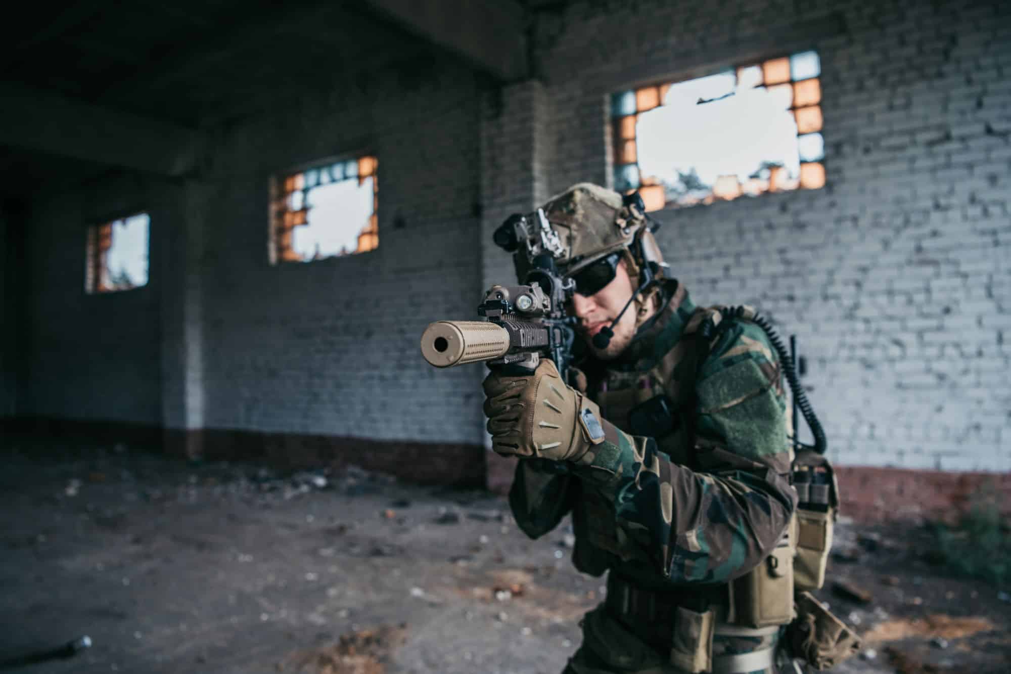 Military soldier in the form holds in the hands an assault rifle, check possible enemies around the